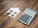 house and key with Calculator on wooden background